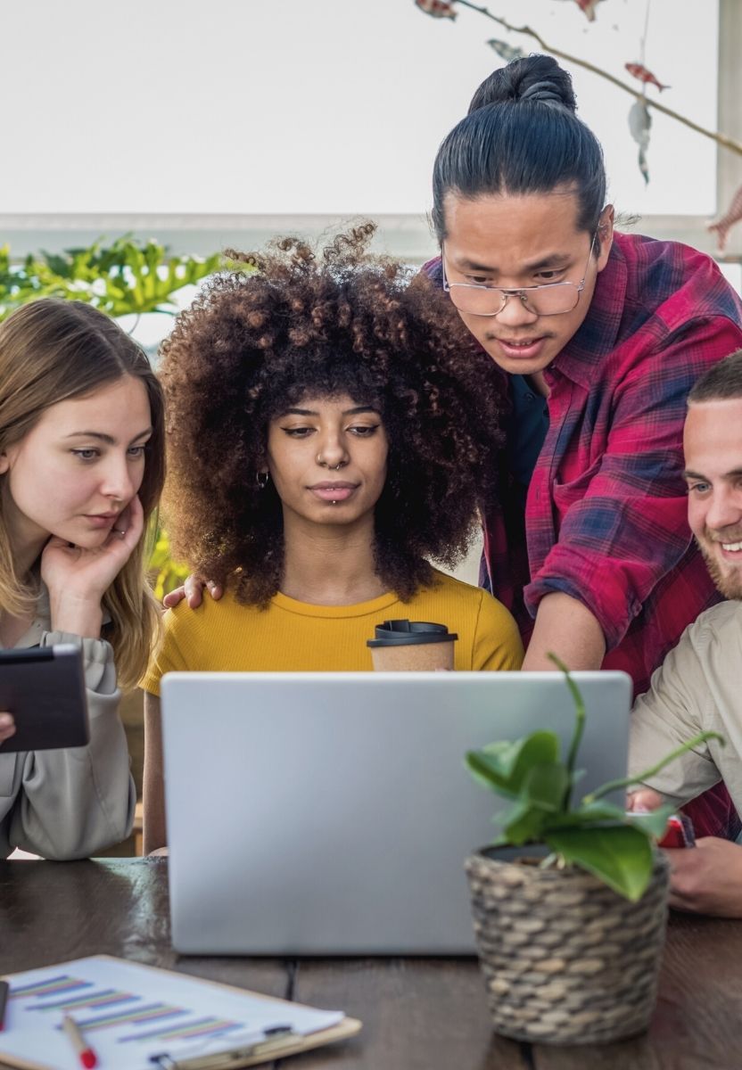 Four Schoolab team members exchanging and looking at a laptop together